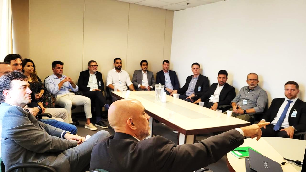 Vários homens conversam em torno de uma mesa.