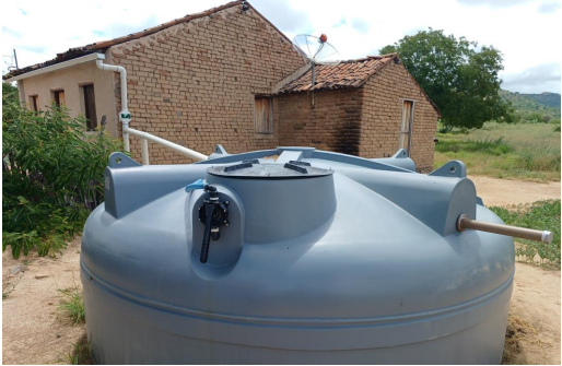 Cisterna instalada em área rural ao lado de residência.
