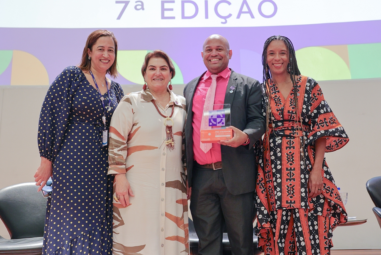 Quatro pessoas posam com troféu do Selo Pró-Equidade em cerimônia oficial