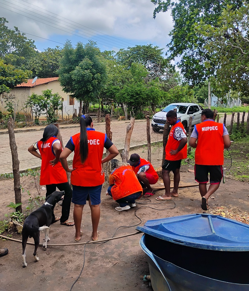 Equipe com coletes laranja realiza atividade em área residencial.