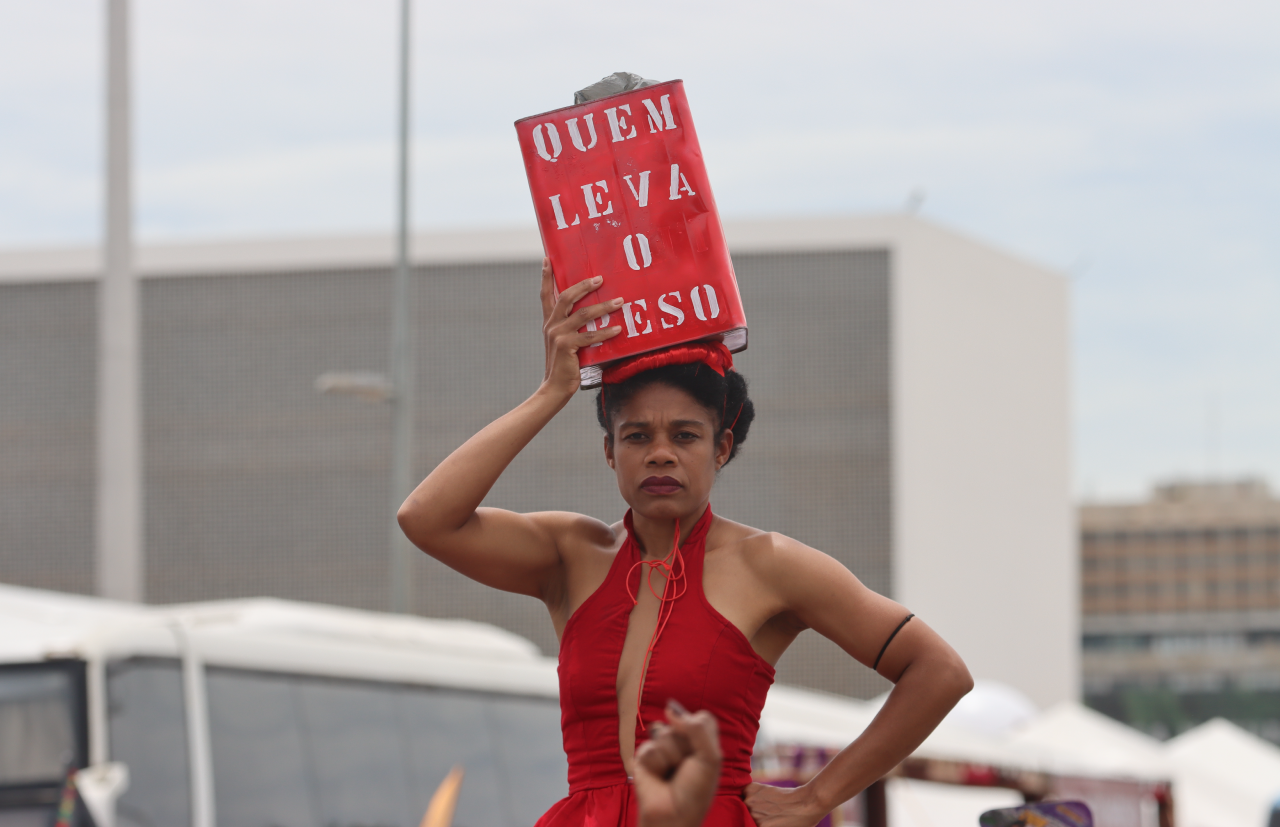 Manifestante na 2ª Marcha Nacional das Mulheres Negras por Reparação e Bem Viver carrega, na cabeça, lata com os dizeres “Quem leva o peso”. Foto: Hugo Aurélio (Ascom/CNS)