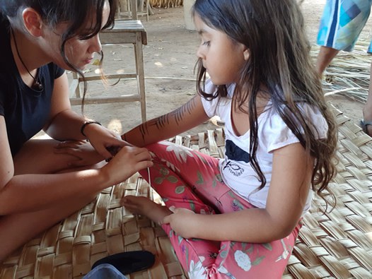 Imagem de mulher pintando uma criança indígena