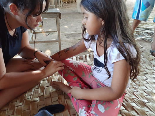 Imagem de mulher pintando uma criança indígena