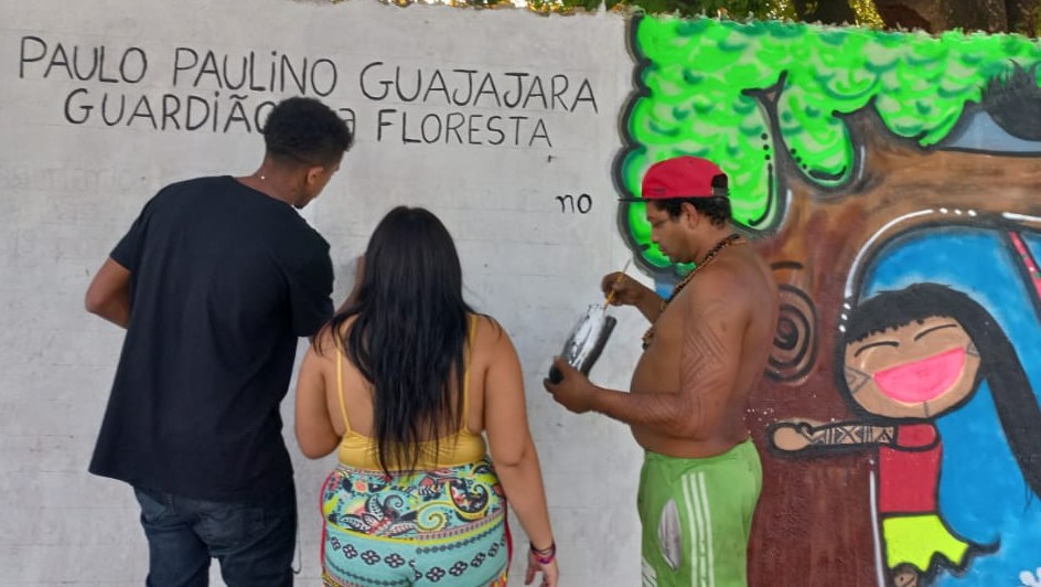 Imagem de pessoas indígenas pintando um muro