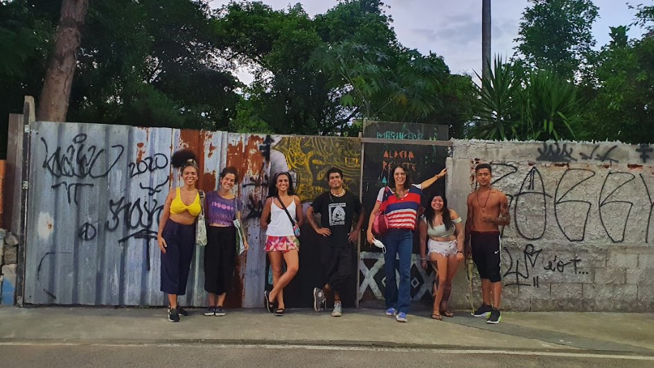 Artistas indígenas em frente ao muro