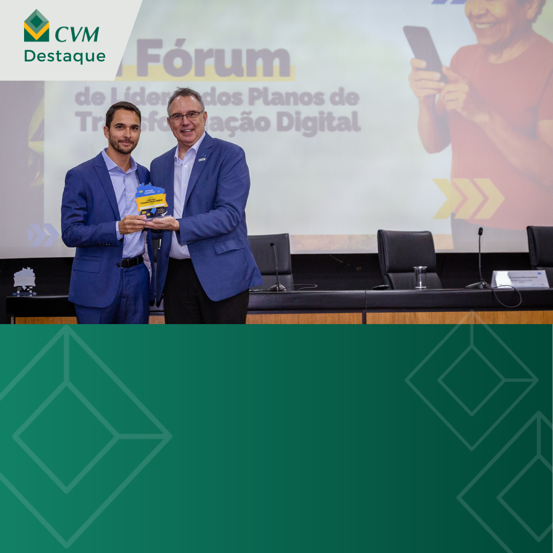 Duas pessoas em um palco, uma segurando um livro, em um evento sobre Transformação Digital.