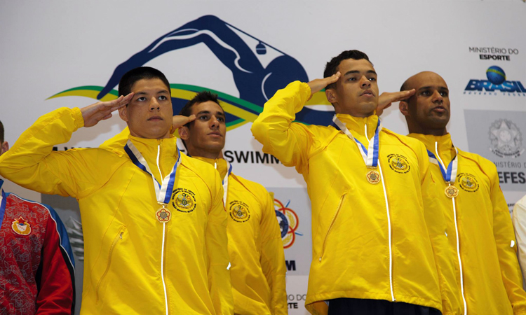Atletas da natação prestam continência no pódio