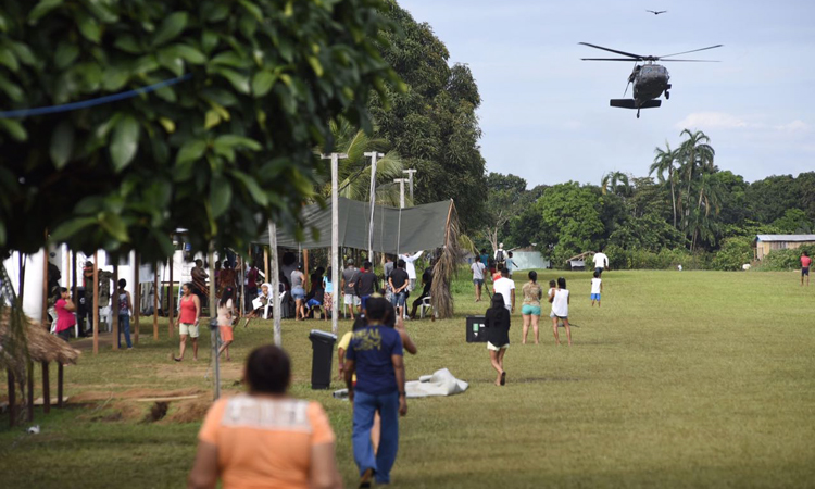 helicóptero se aproxima para o pouso e muitas pessoas se aproximam para ver.