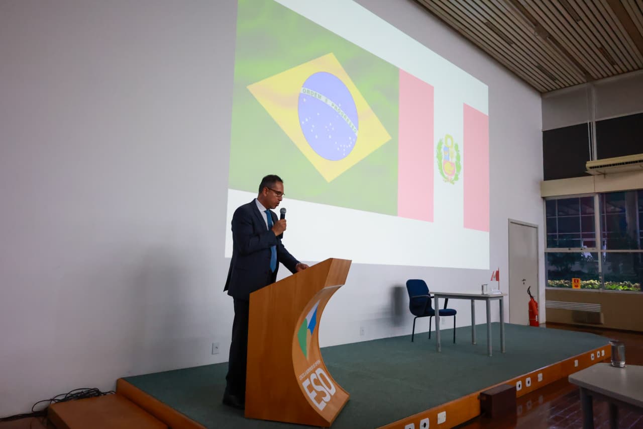 Embaixador do Peru no púlpito. Ao fundo, a bandeira do Brasil e do Peru projetadas na tela