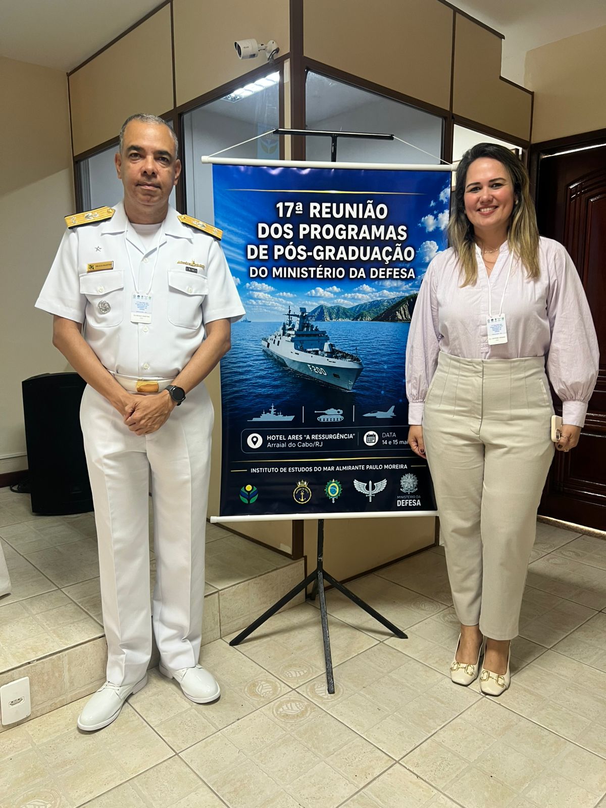 Calte Braga Martins e Professora Cintiene em frente ao banner do evento.
