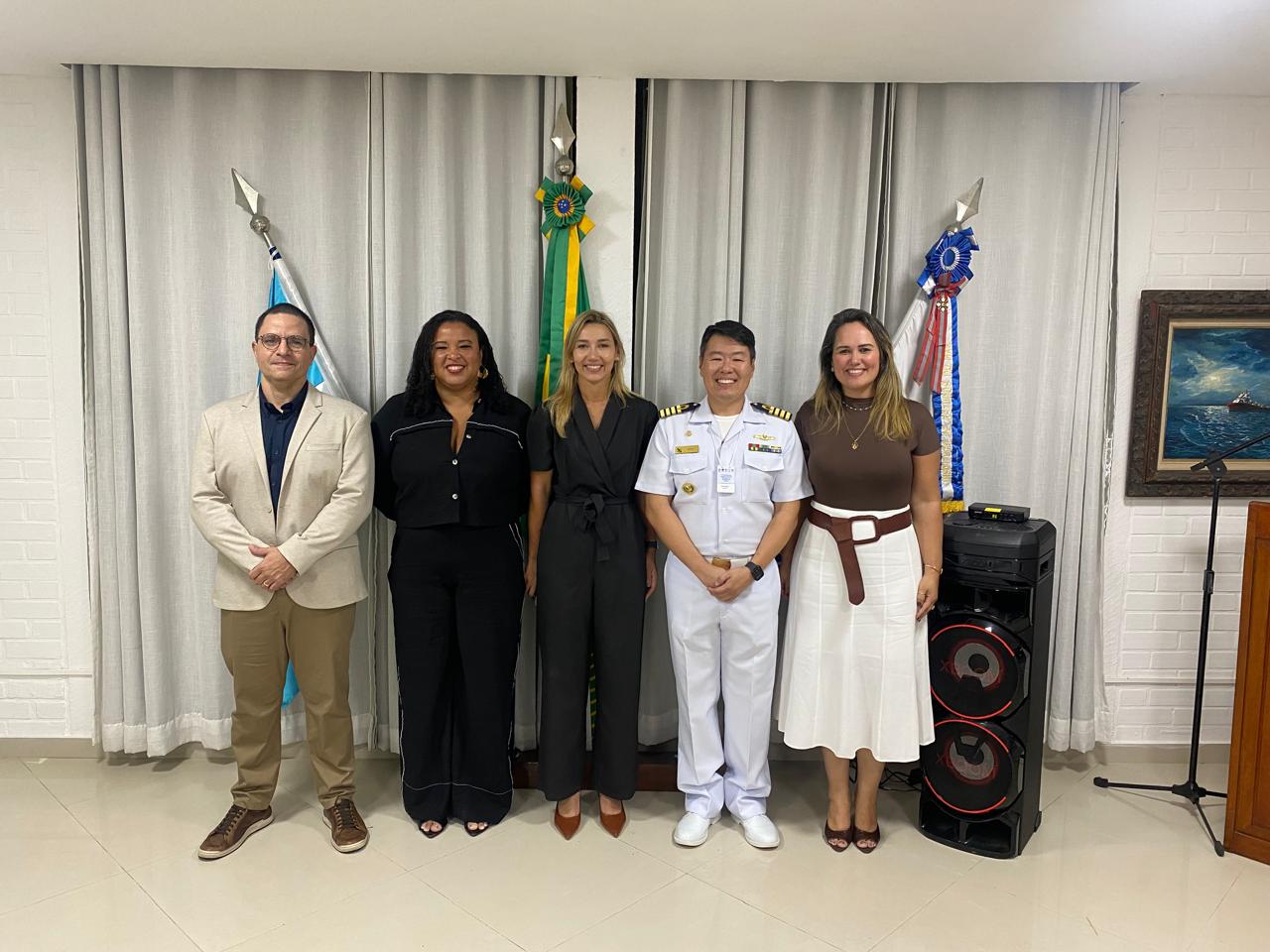Prof. Cintiene com 4 colegas, sendo um militar e 3 civis sorrindo em pé olhando para a câmera.