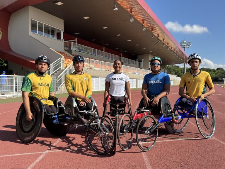 Cinco atletas em cadeiras de roda posam para foto.