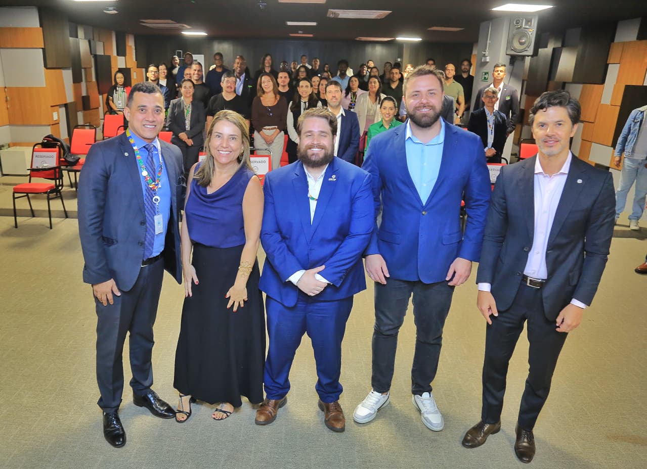 Quatro homens e mulher posam de pé e ao fundo está a plateia