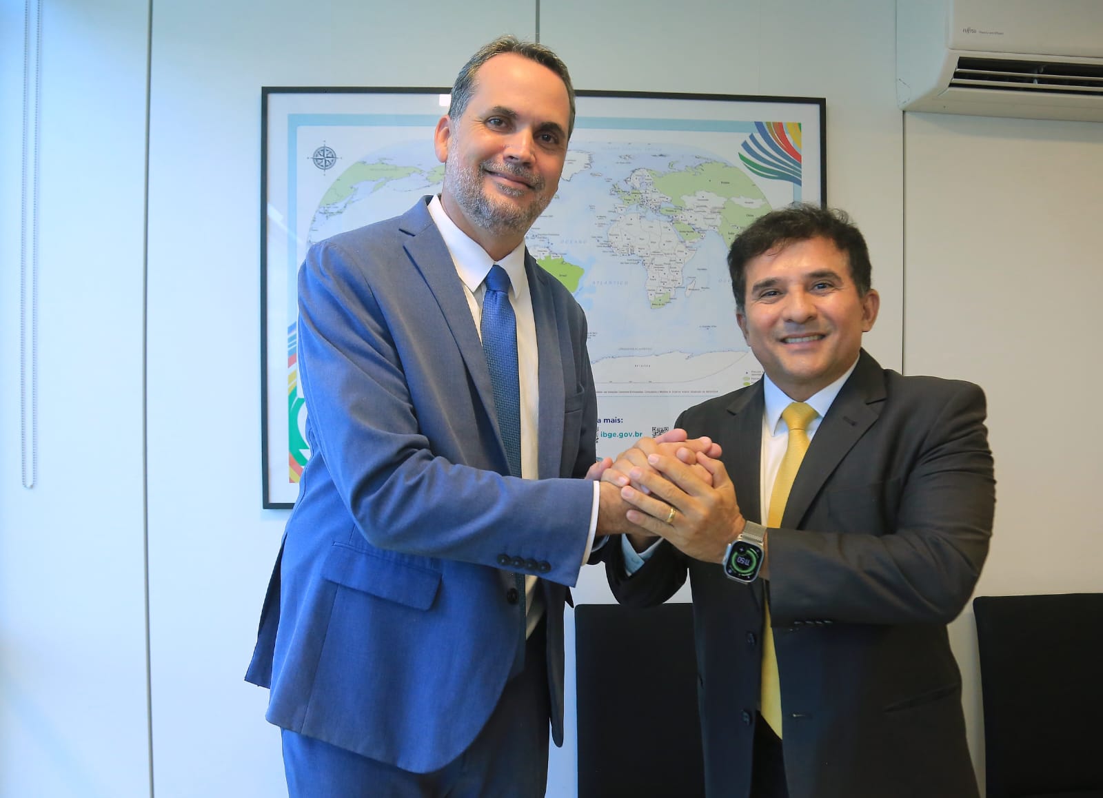 Ministro Bruno Moretti, de terno e gravata azuis, cumprimenta o ministro Paulo Henrique Cordeiro, de terno preto e gravata amarela.