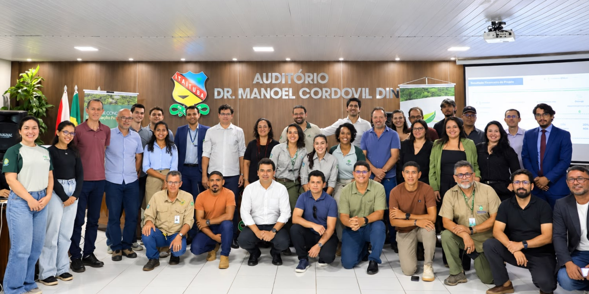 Fotografia colorida de um grupo de aproximadamente 23 pessoas reunidas para uma foto coletiva