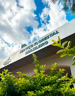 Fotografia em plano baixo da fachada de um edifício institucional. Na parte superior, há a inscrição