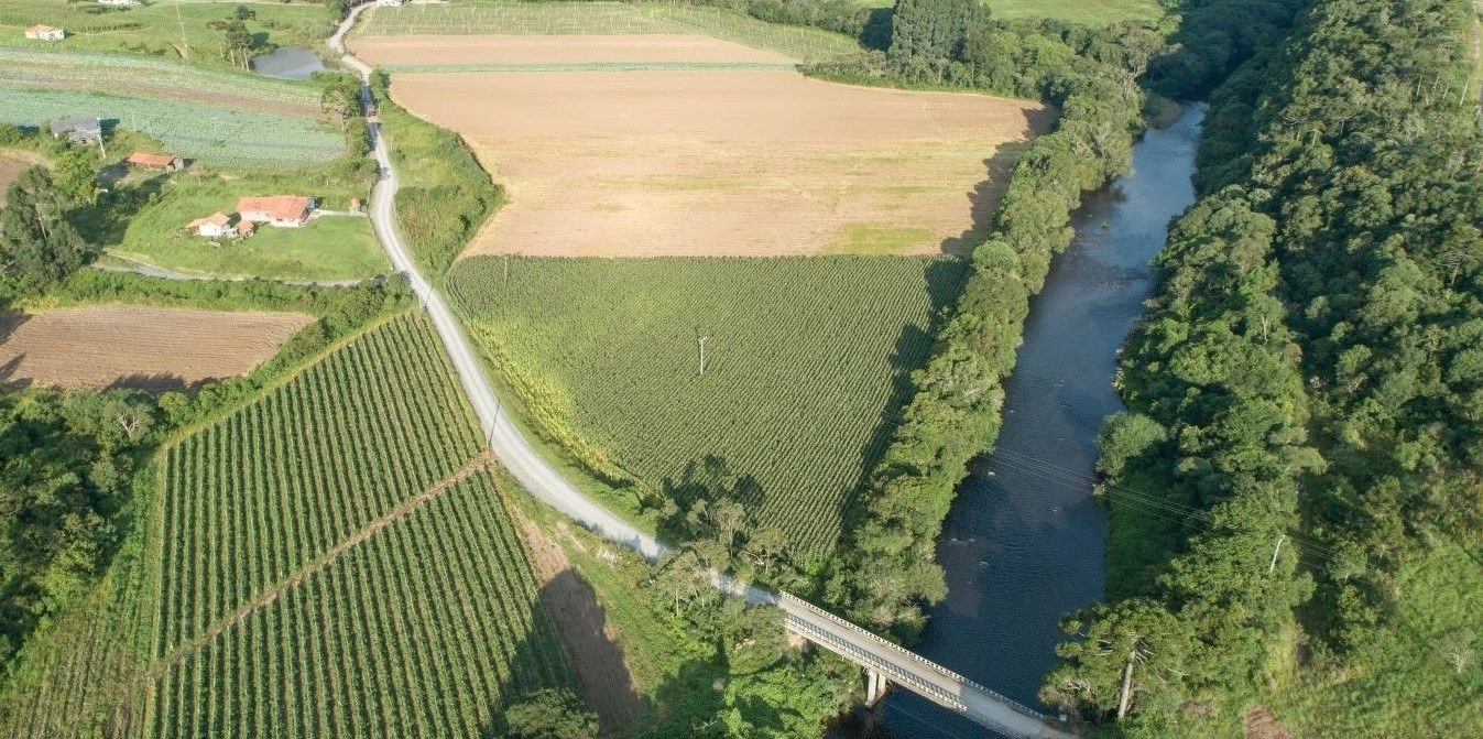 Vista aérea de imóvel rural, com áreas produtivas e vegetação nativa, cenário que ilustra a análise do Cadastro Ambiental Rural (CAR) e a regularização ambiental das propriedades.