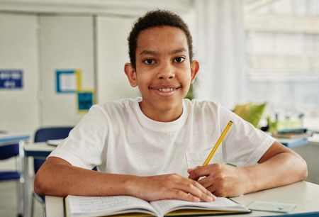 Jovem brasileiro em ambiente escolar utilizando livro didático.
