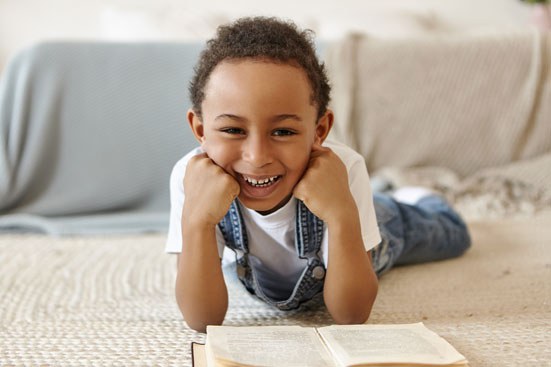 portrait-schoolboy-lying-floor-reading-book-library-school.jpg