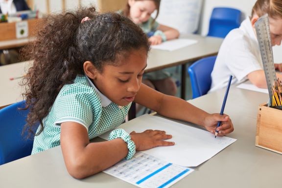 schoolgirl-writing-at-classroom-desk-in-primary-sc-2022-03-04-01-48-58-utc.jpg