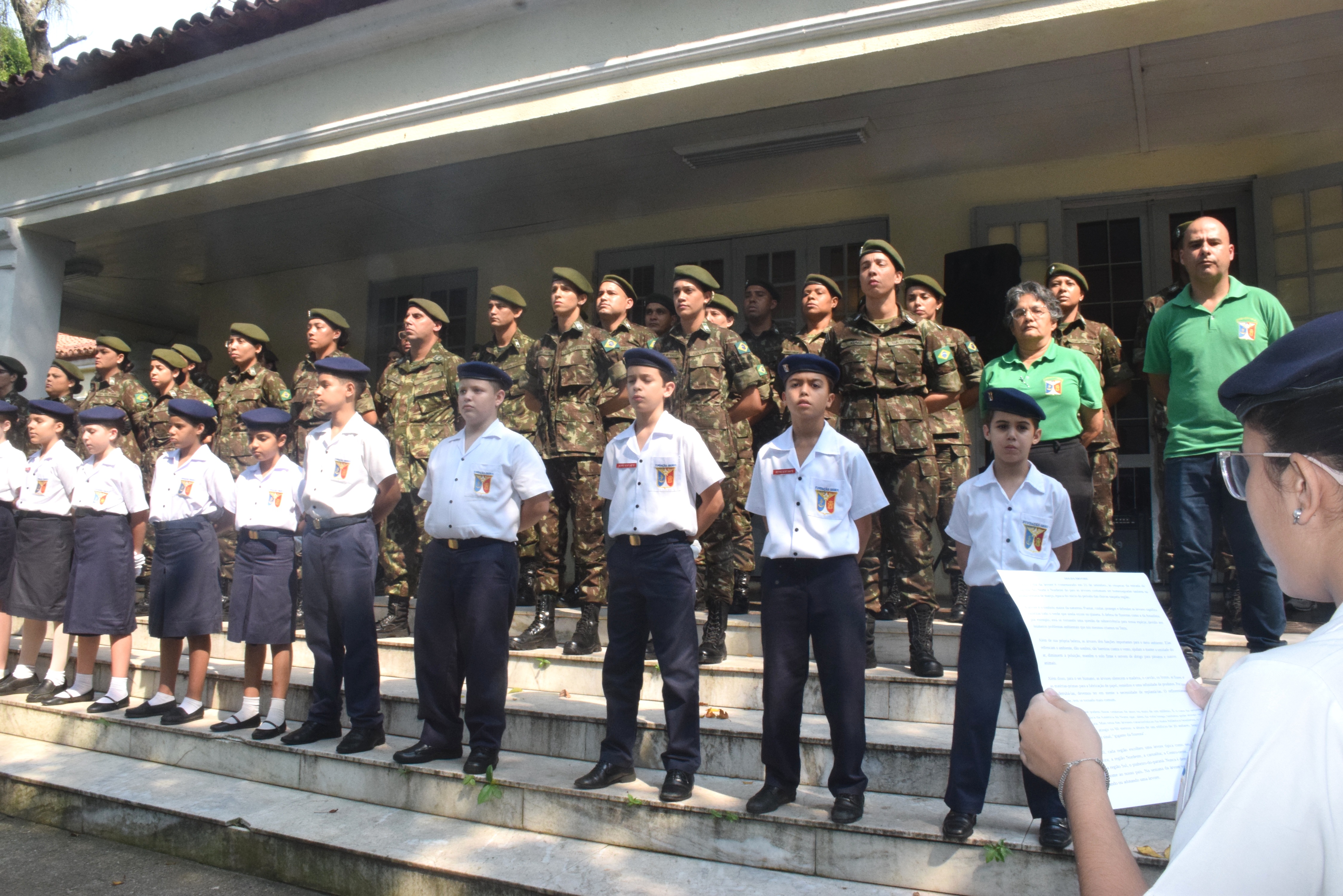 Formação de alunos fardados e militares em escadaria, durante cerimônia ou atividade cívica relacionada ao Dia da Árvore.