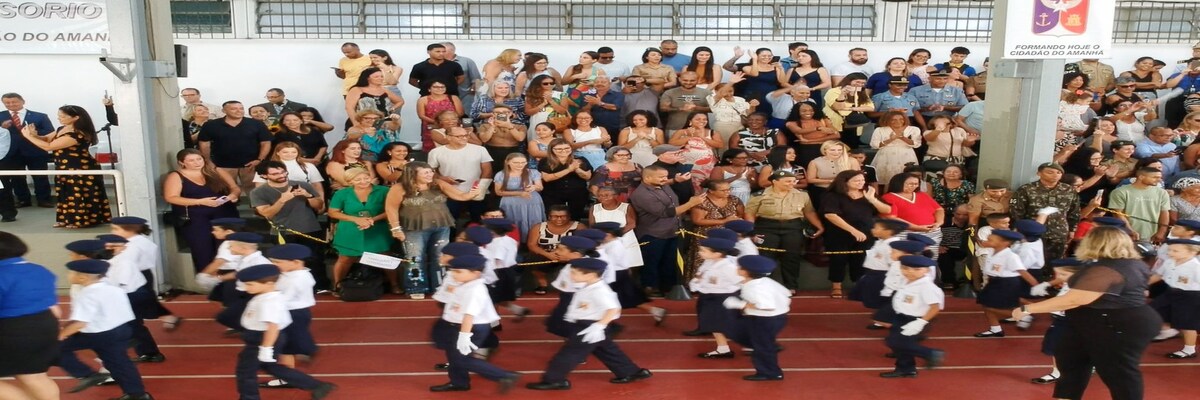 Crianças uniformizadas desfilam diante de familiares em cerimônia escolar militar.