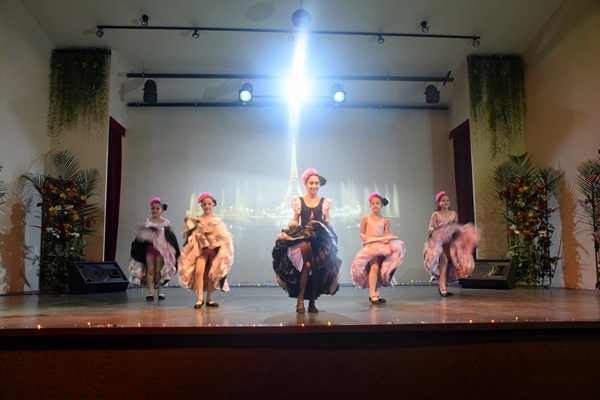 Grupo de bailarinas dançando com figurinos coloridos em apresentação no palco.