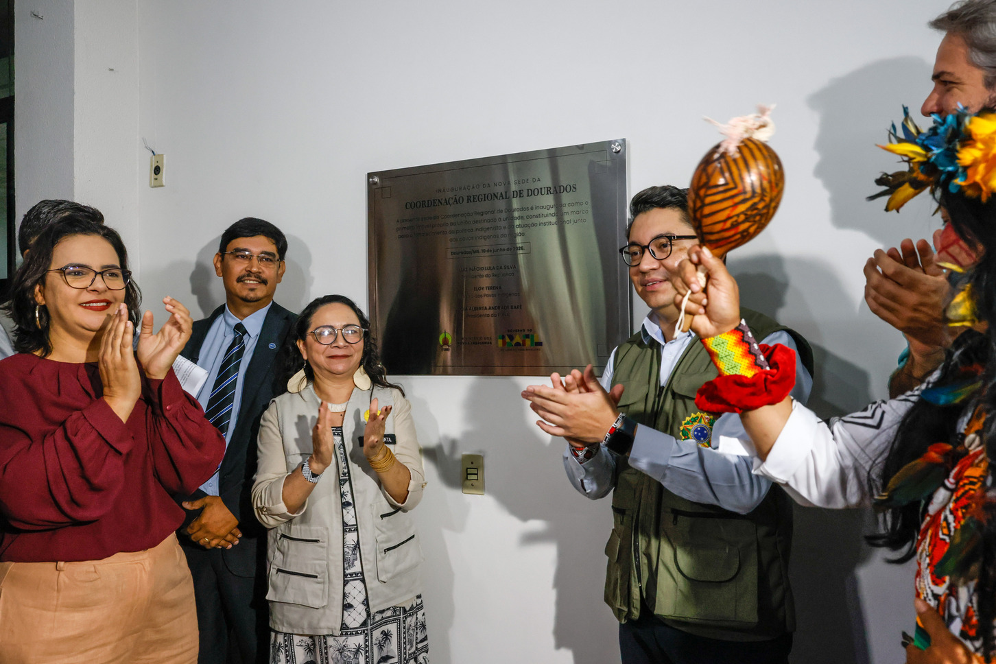 4 pessoas aplaudindo e uma placa ao fundo