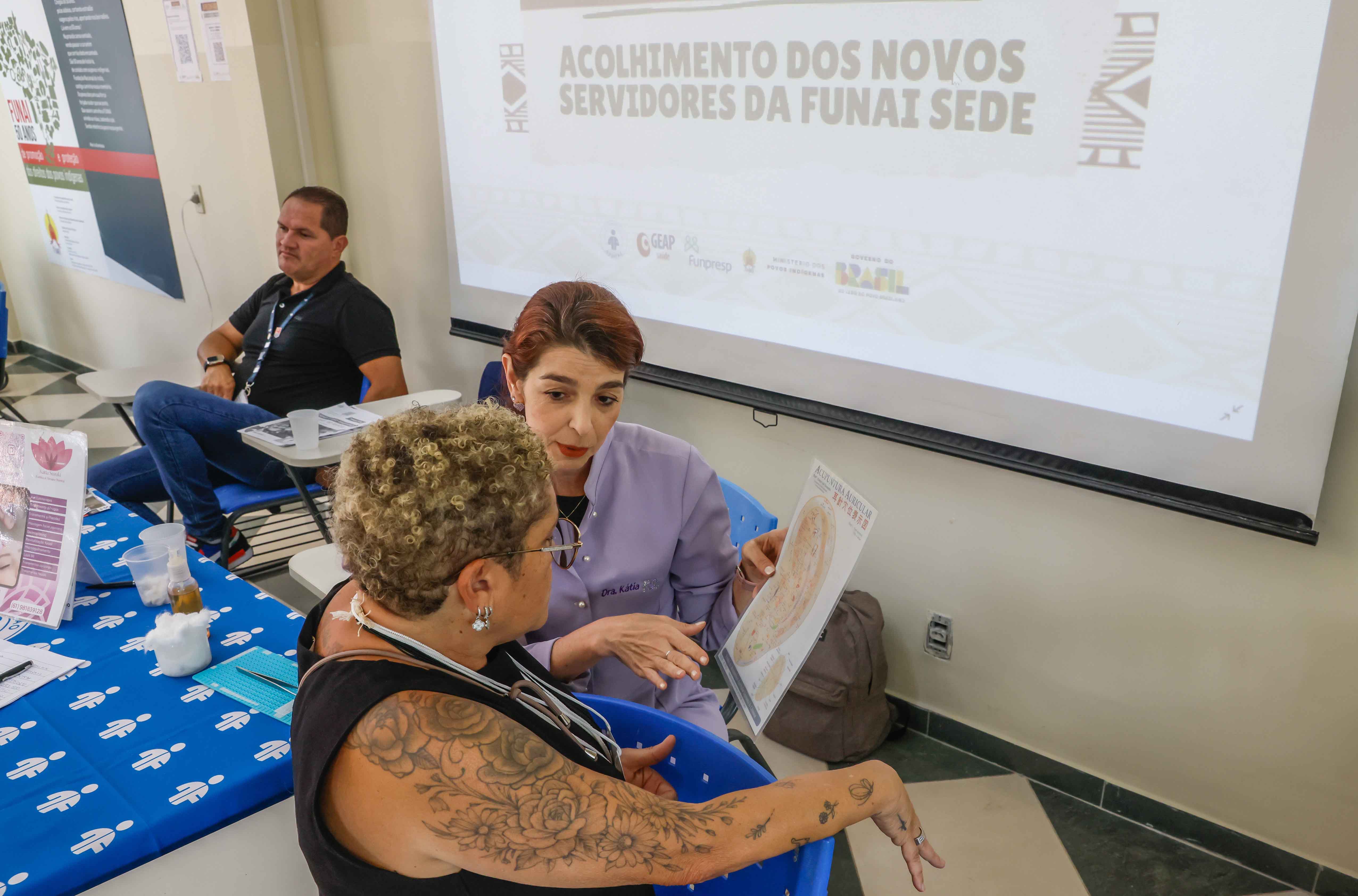uma mulher explicando a outra os pontos auriculares