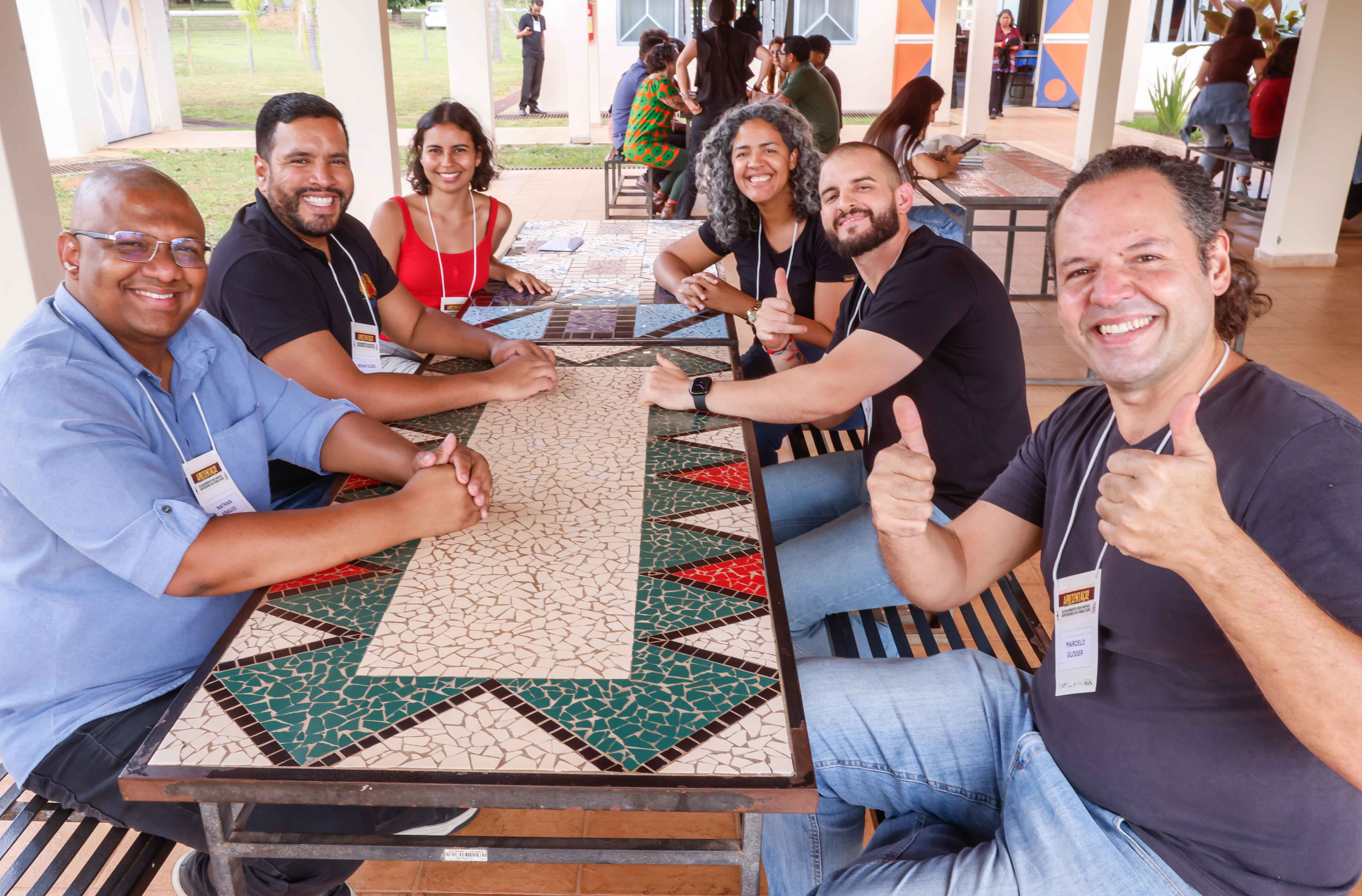 grupo de pessoas ao redor de uma mesa olhando para foto