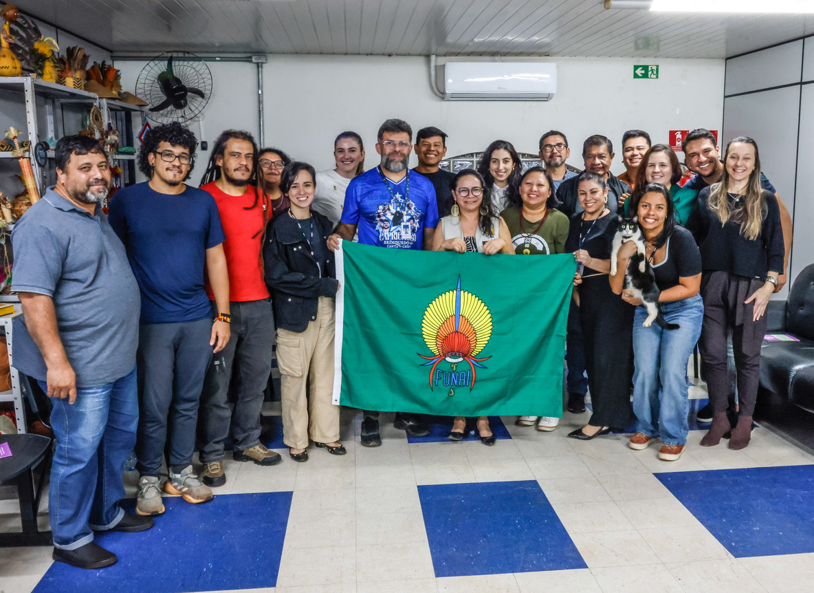 Servidores em pé segurando a bandeira da Funai