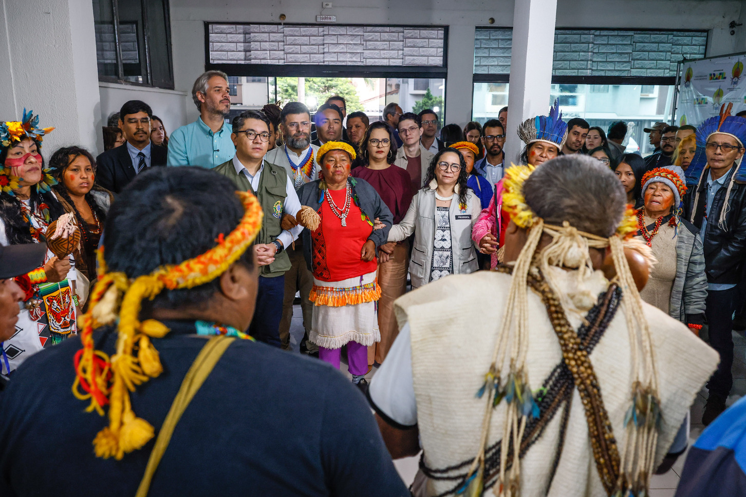 Diversas pessoas em pé de mãos dadas formando uma roda