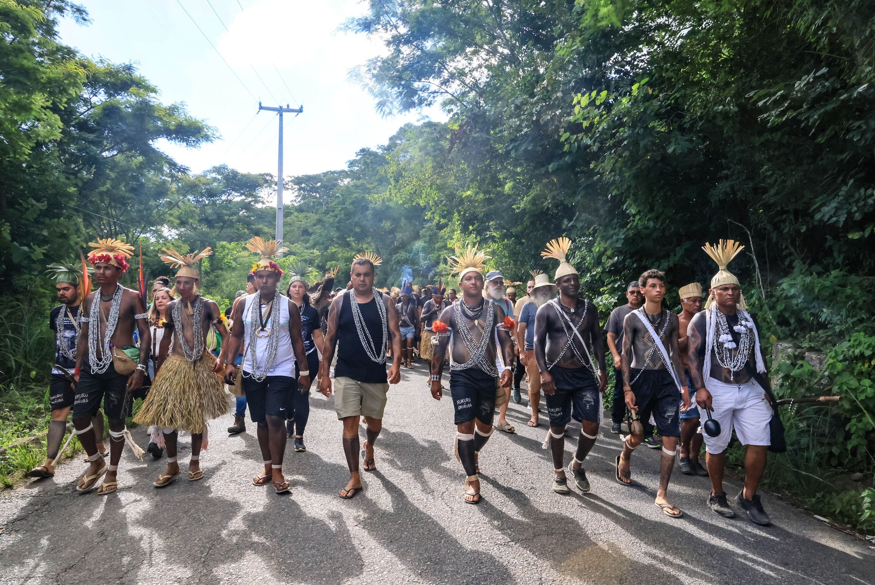 Indígenas do povo Xukuru marchando uns ao lado dos outros usando adereços tradicionais.