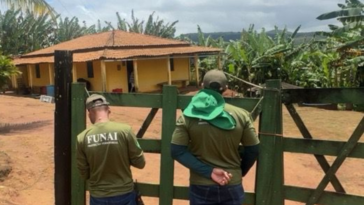 Agentes da Funai atrás de portão de área rural