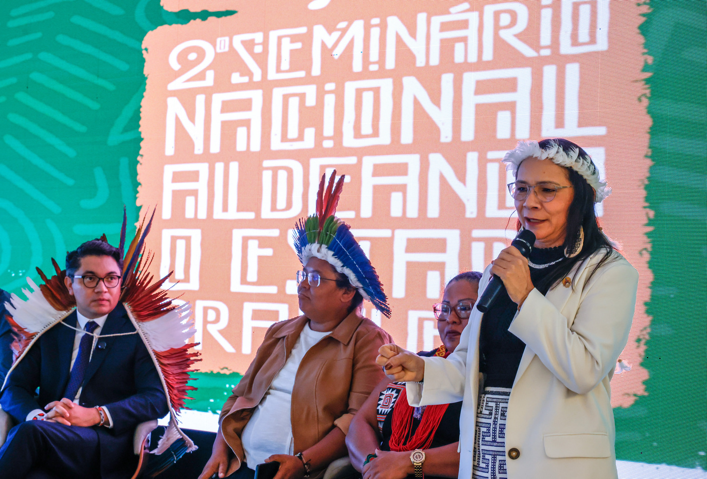 Representantes indígenas de órgãos indigenistas discursam no palco durante seminário