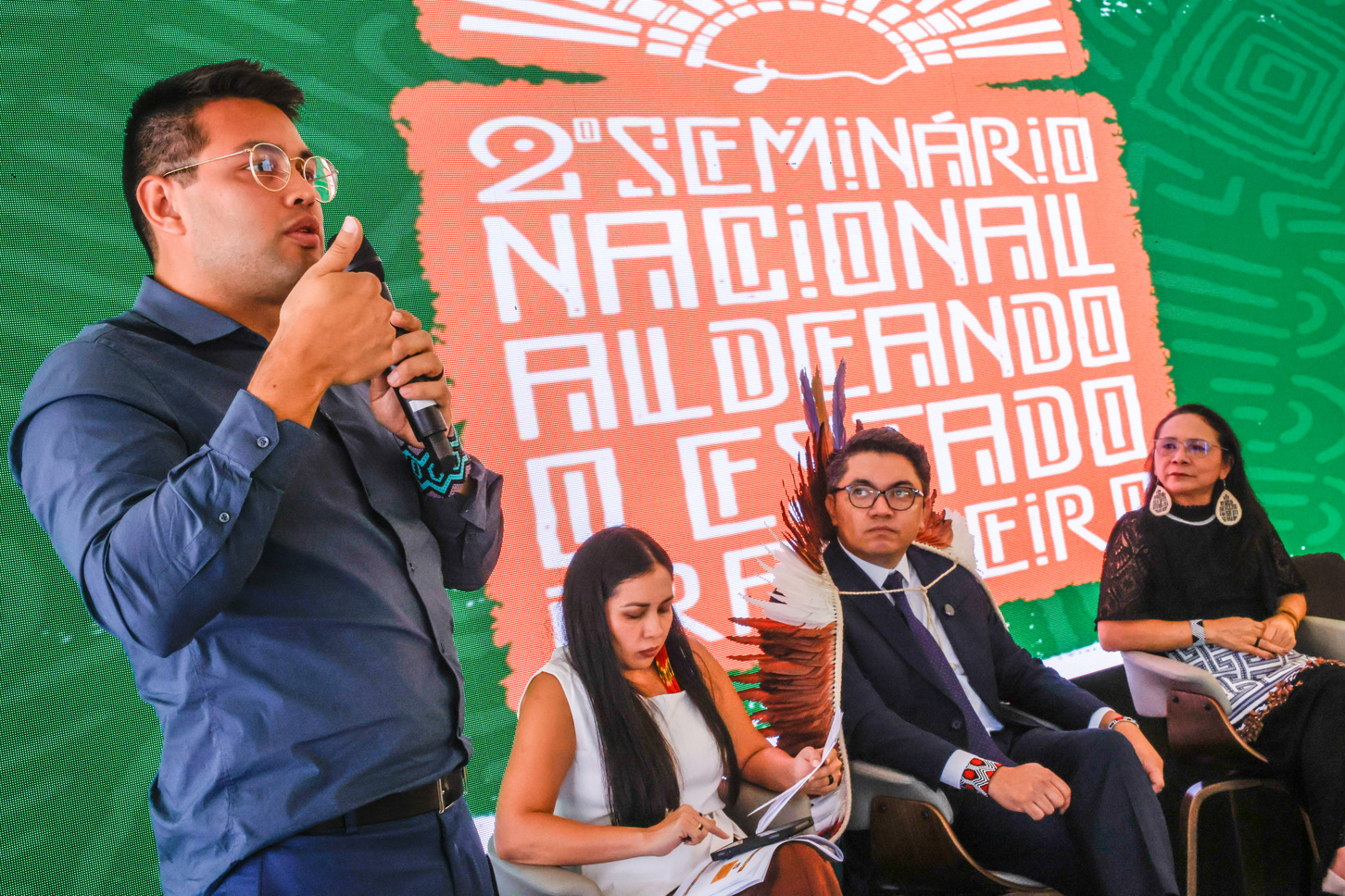 Representante de organização indígena fala ao microfone durante seminário