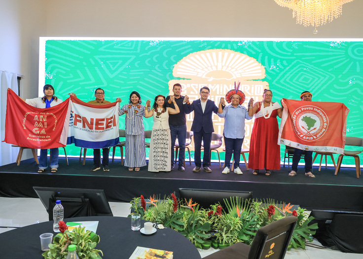 Representantes de organizações indígenas seguram bandeiras de suas instituições no palco