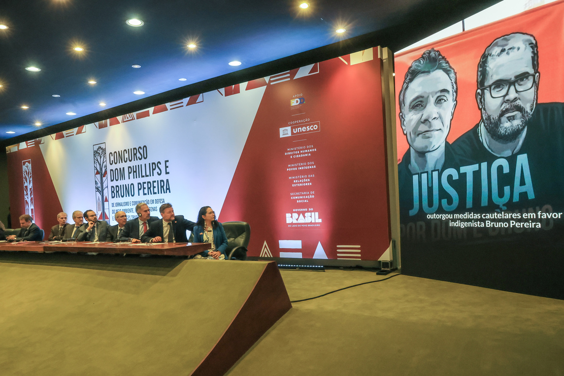 autoridades olhando para telão escrito justiça e com a imagem de Dom e Bruno