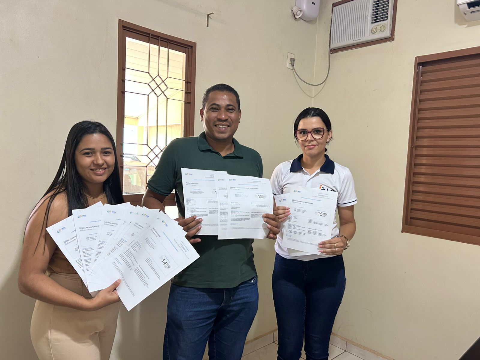 Duas mulheres e um homem mostram as documentações emitidas durante o mutirão