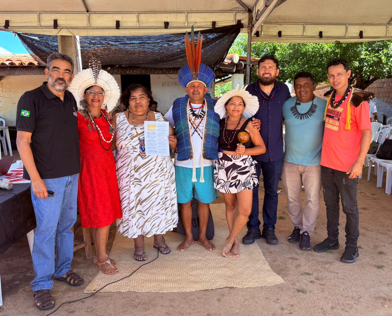 Indígenas e integrantes da Funai mostrando documento