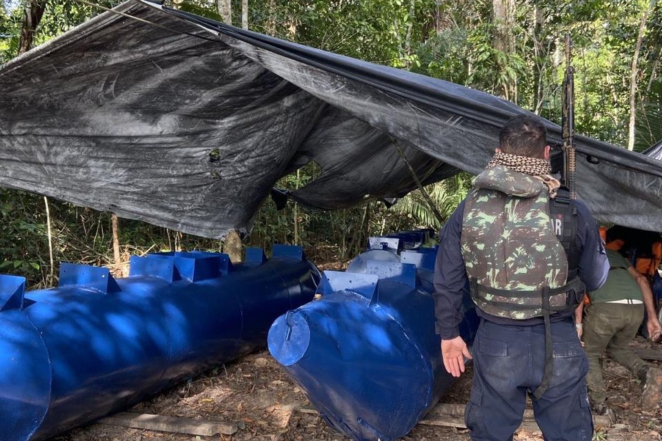 Homem de costas em frente a um acampamento ilegal
