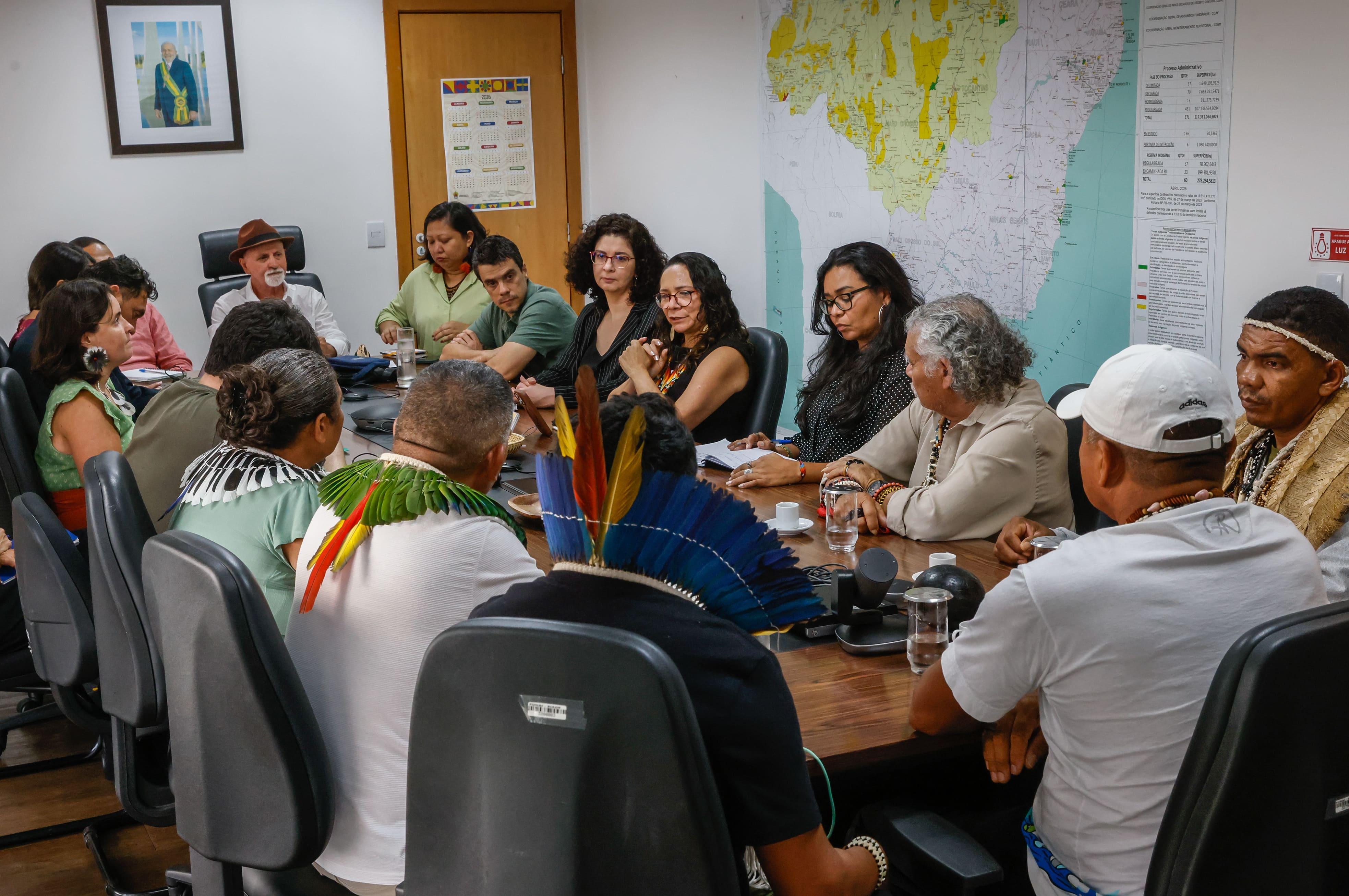 Reunião em escritório com várias pessoas sentadas em uma mesa longa, incluindo lideranças indígenas
