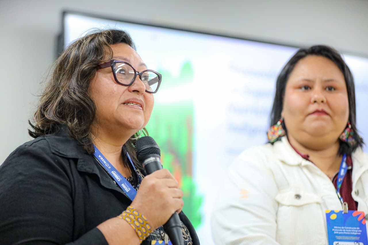 2 mulheres em pé uma com microfone falando