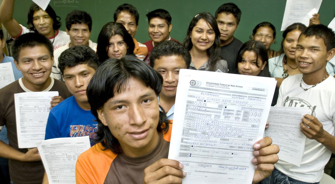 Imagem de estudantes indígenas em sala de aula mostrando suas notas