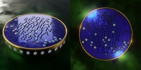 Imagem mostra dois círculos representando a frente e o verso de uma medalha. Na parte da frente, a medalha está deitada e é na cor azul forte. Possui as laterais douradas e cheias de pedras brilhantes em volta. Na área azul, está escrito em letras grandes e maiúsculas 2022 Bicentenário Independência Brasil 1822. Também há brilhantes misturados às letras. Na parte de trás, a medalha está de pé e apresenta a mesma estética da frente.  