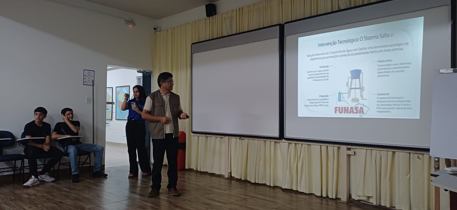 Palestrante apresenta slide sobre o Sistema Salta-z para estudantes em sala.