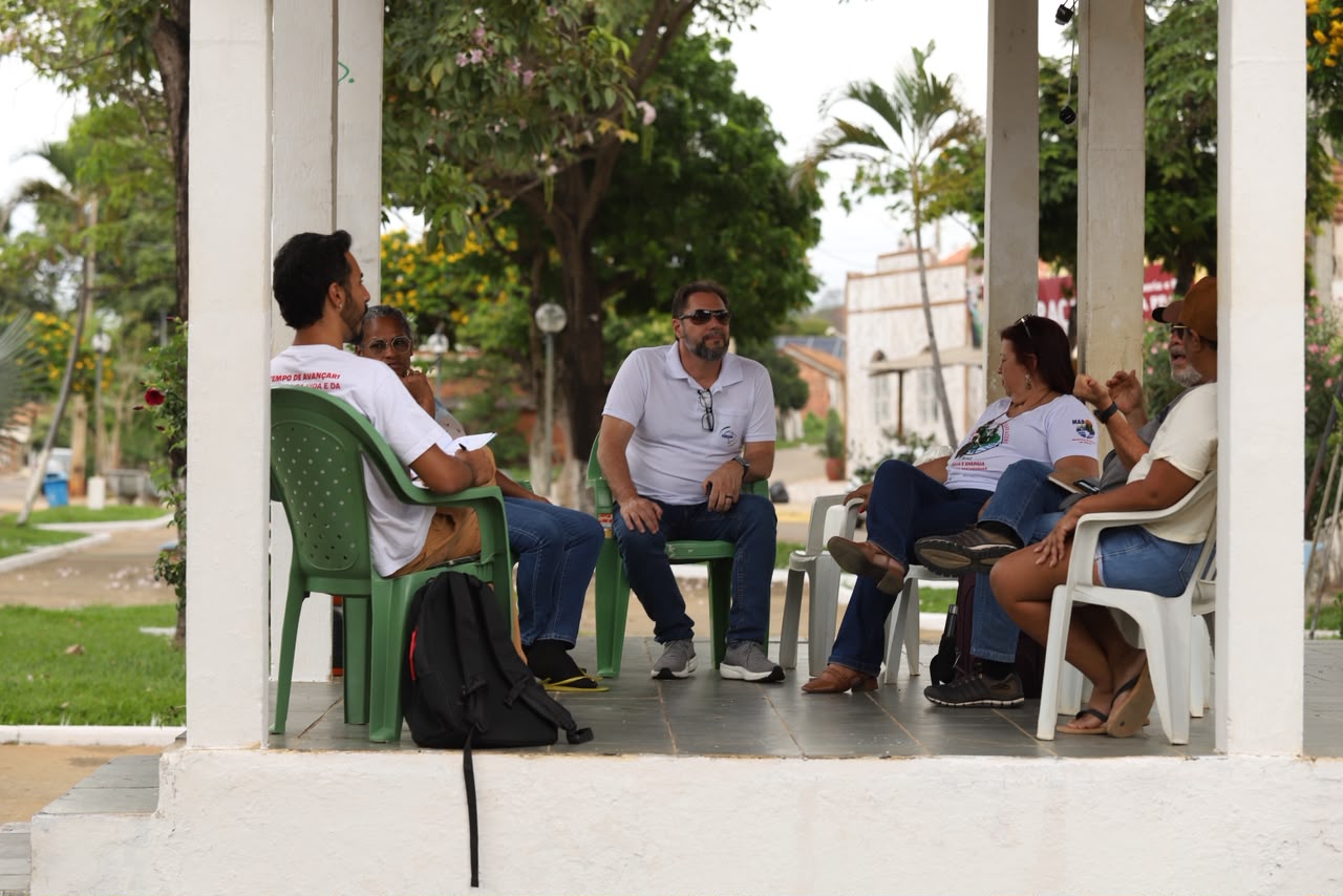 Grupo de pessoas sentado em cadeiras em área coberta ao ar livre conversando em roda.