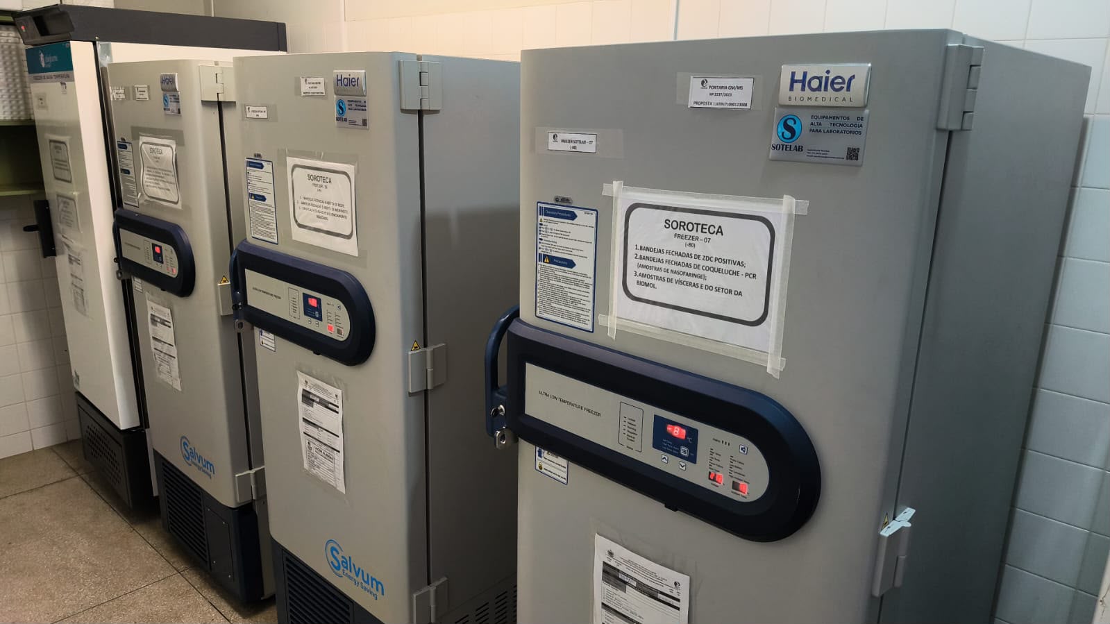 Ultrafreezers laboratoriais de grande porte com visores digitais e avisos nas portas.