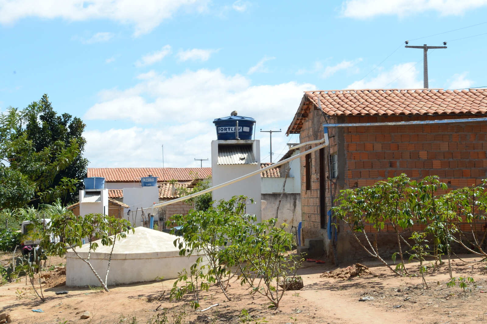 Casa de tijolos com sistema de captação de chuva ligado a cisterna e caixas d'água.