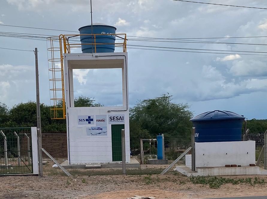 Torre branca com caixa-d'água azul no topo e logos do SUS, Funasa, Sesai e Salta-Z na parede.